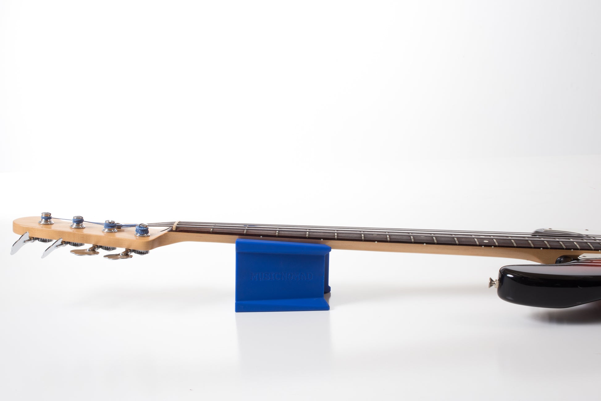 MUSIC NOMAD MN206 CRADLE CUBE DEMO PHOTO BASS GUITAR RESTING ON CRADLE CUBE ON WHITE BACKGROUND
