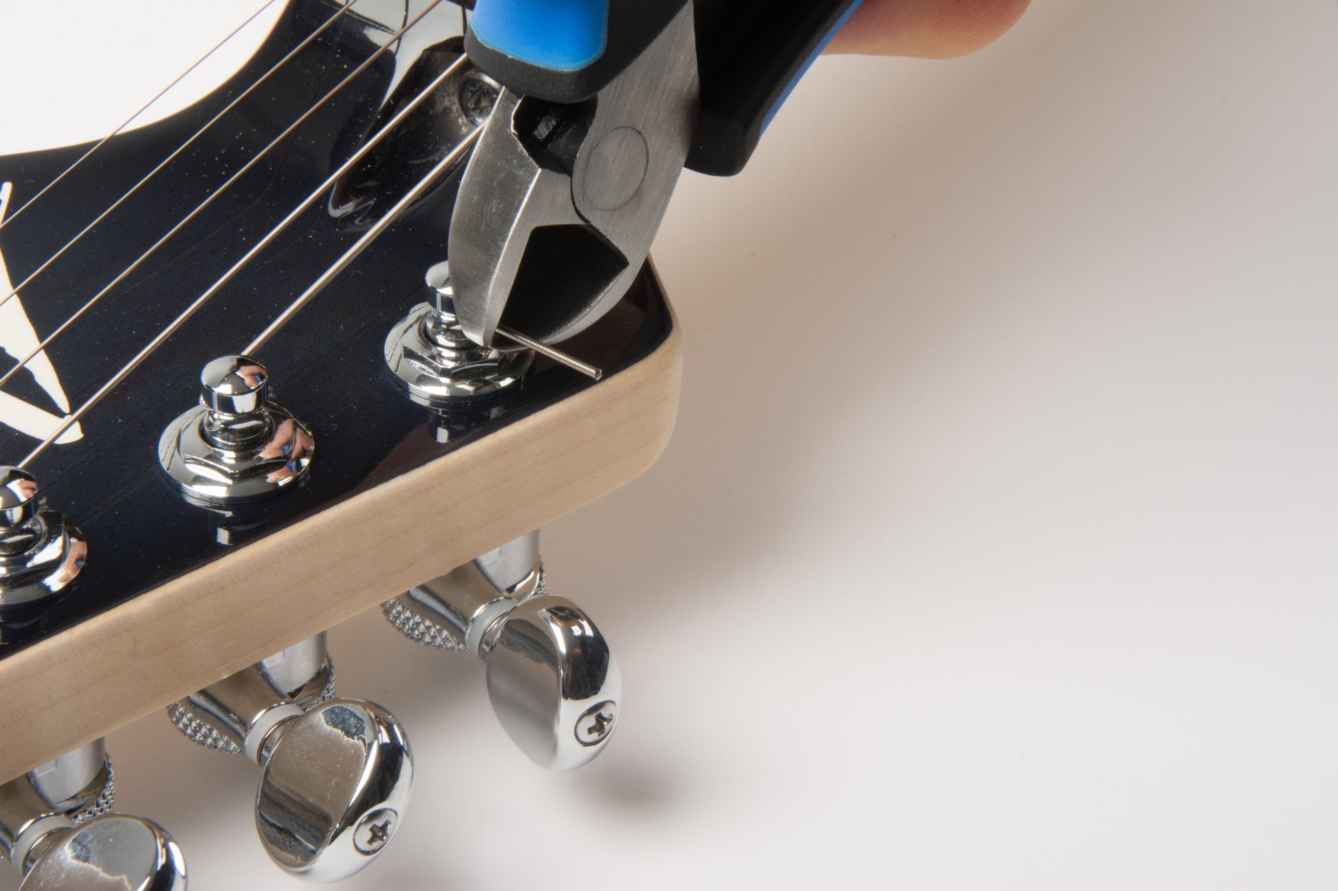 MUSIC NOMAD MN226 MUSICNOMAD GRIP CUTTER ZOOM HAND CUTTING STRING ON TUNING PEG ON WHITE BACKGROUND