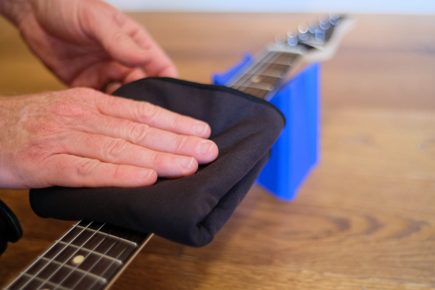 MusicNomad mn241 DEMO PHOTO GUITAR ON STAND POLISHED BY HAND ON BROWN WOOD BACKGROUND