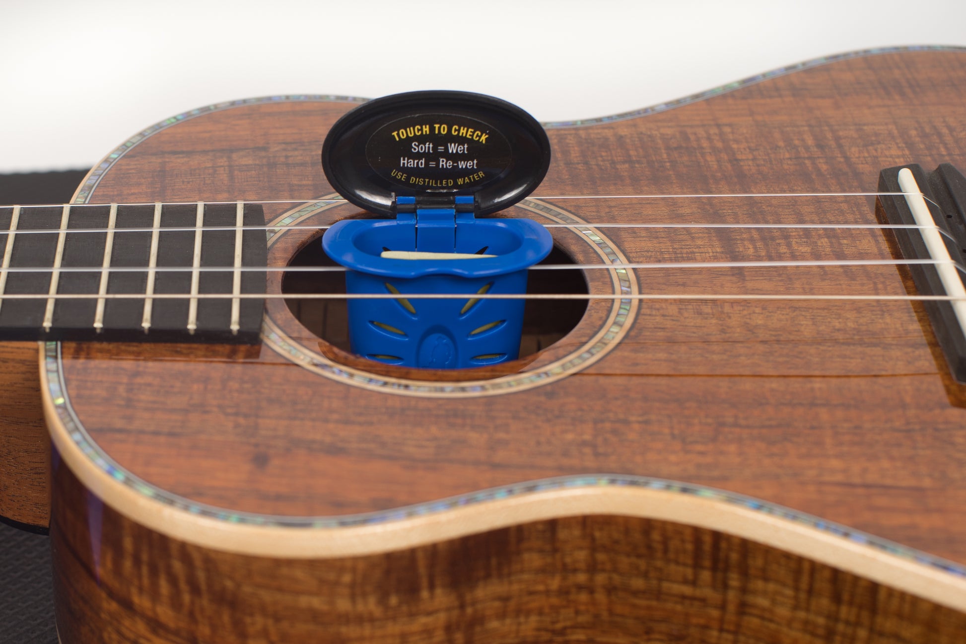 MUSICNOMAD MN302 HUMILILE HUMIDIFIER FRONT ANGLED OPEN VIEW OF SPONGE AND IN UKULELE SOUND HOLE ON WHITE BACKGROUND