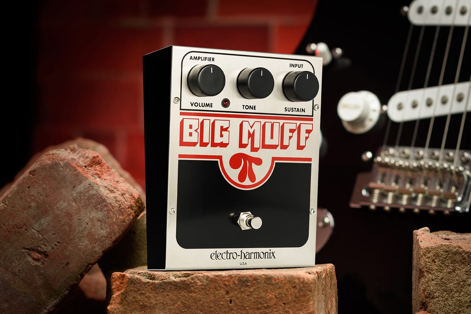  ELECTRO-HARMONIX EHX U.S. BIG MUFF PI PROMO PHOTO FRONT AND LEFT SIDE VIEW ON RED BRICKS WITH BLACK GUITAR AND RED BRICK BACKGROUND